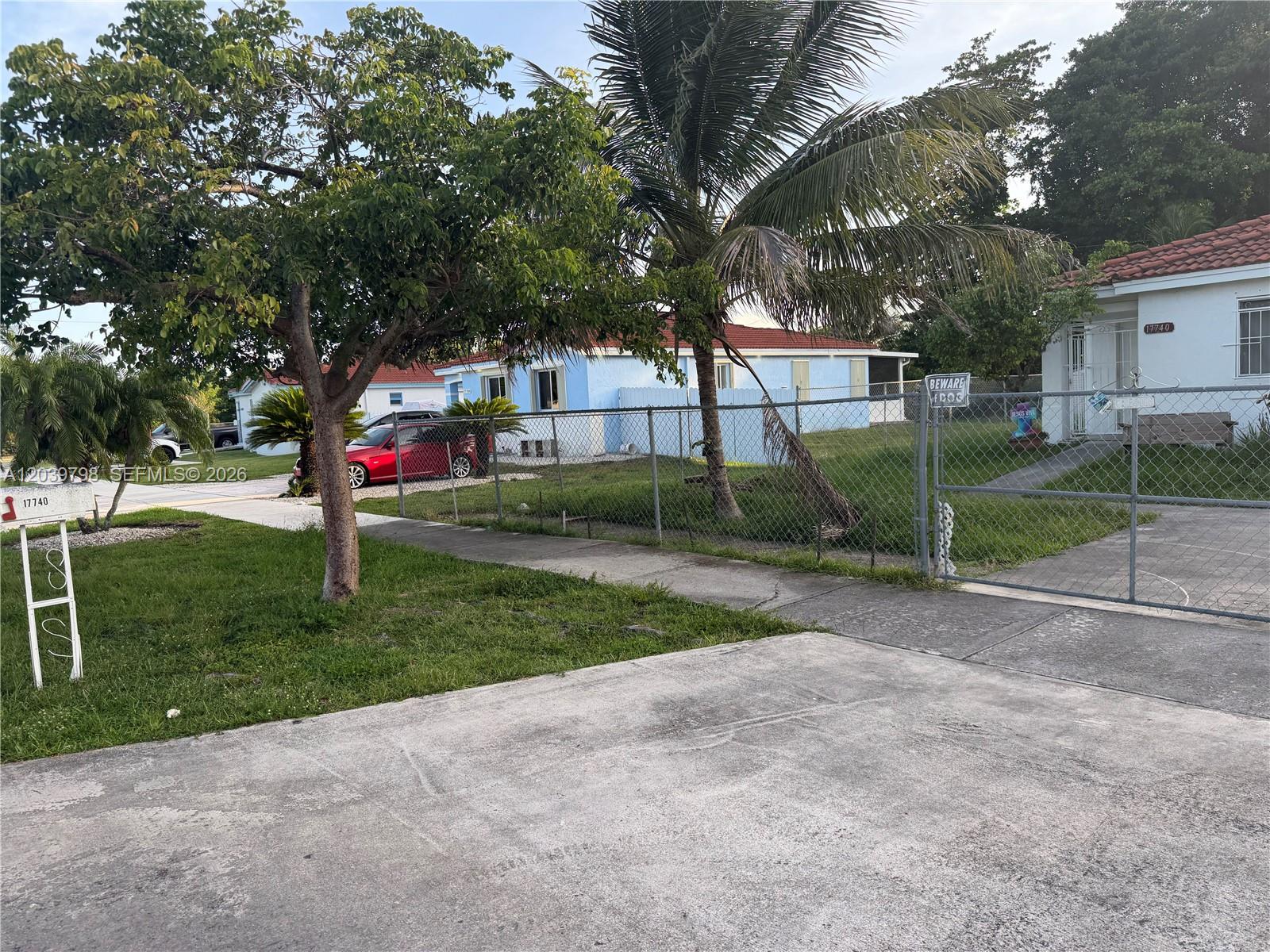 A light blue house with a red roof sits behind a chain-link fence — 17740 SW 103rd Ave # 0, Miami FL 33157, MIAMI, FL