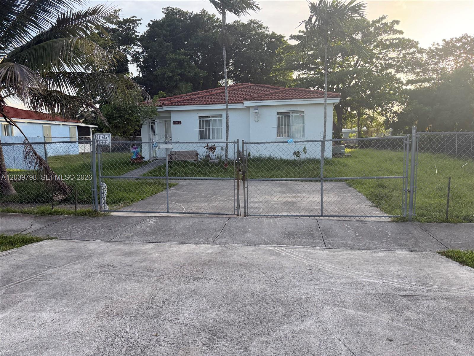 A white single-story house with a red tile roof sits behind a chain-link fence — 17740 SW 103rd Ave # 0, Miami FL 33157, MIAMI, FL