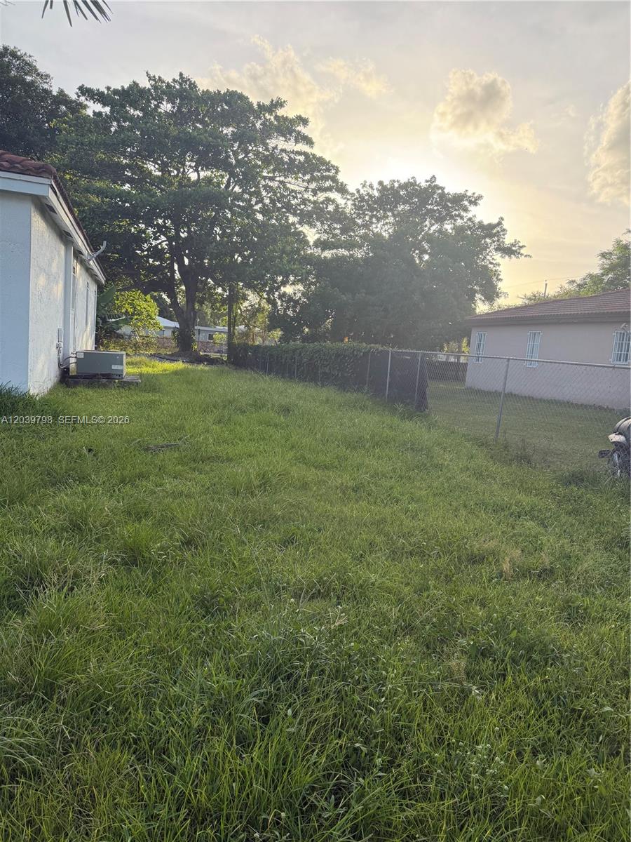 A grassy backyard features a chain-link fence, mature trees, and an adjacent house exterior — 17740 SW 103rd Ave # 0, Miami FL 33157, MIAMI, FL