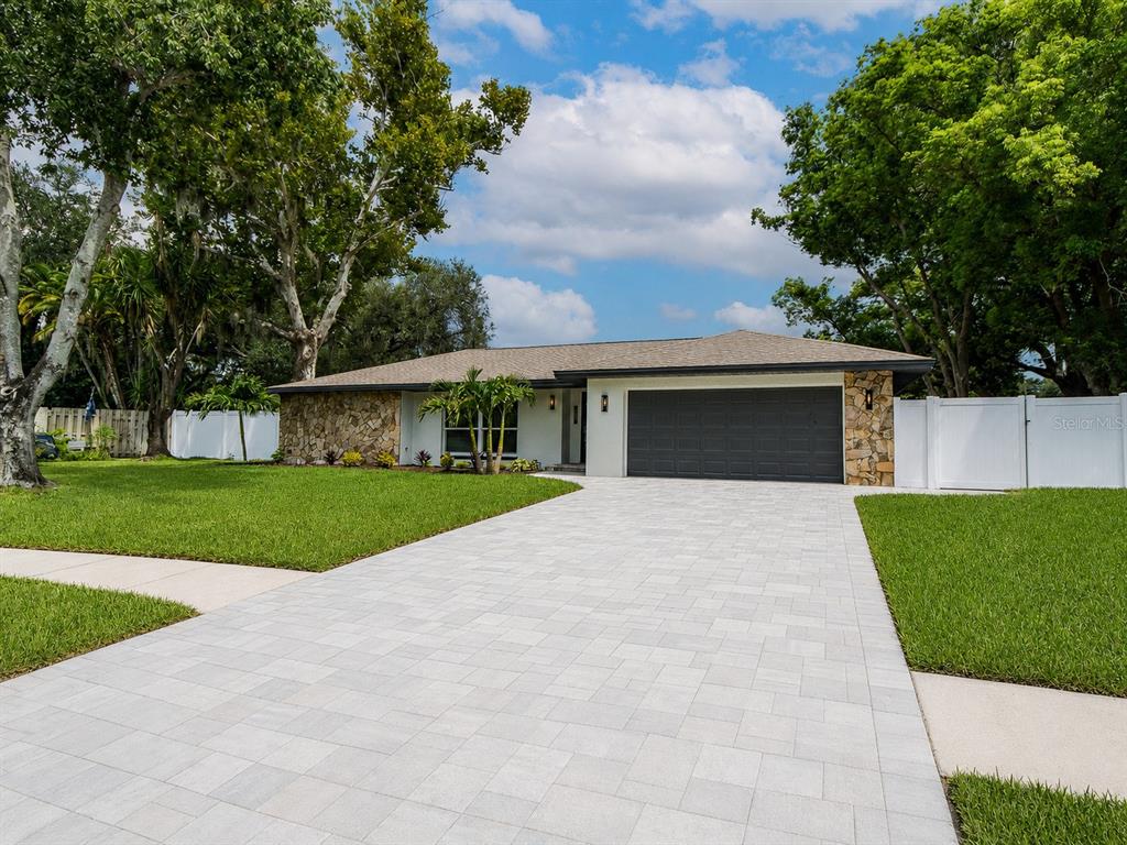 A large backyard with a mature tree and a screened-in pool behind a house — 1967 CASTILLE DRIVE, DUNEDIN, FL