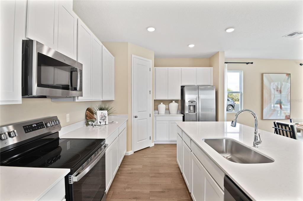 A modern kitchen features white cabinets, stainless steel appliances, and a large central island — 2529 29TH LANE E, PALMETTO, FL