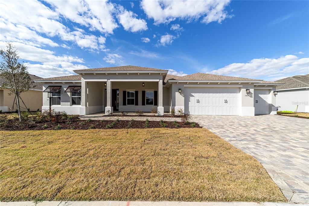 A single-story house with a beige stucco exterior, a paved driveway, and a covered entryway — 10071 SW 82ND PLACE ROAD, OCALA, FL