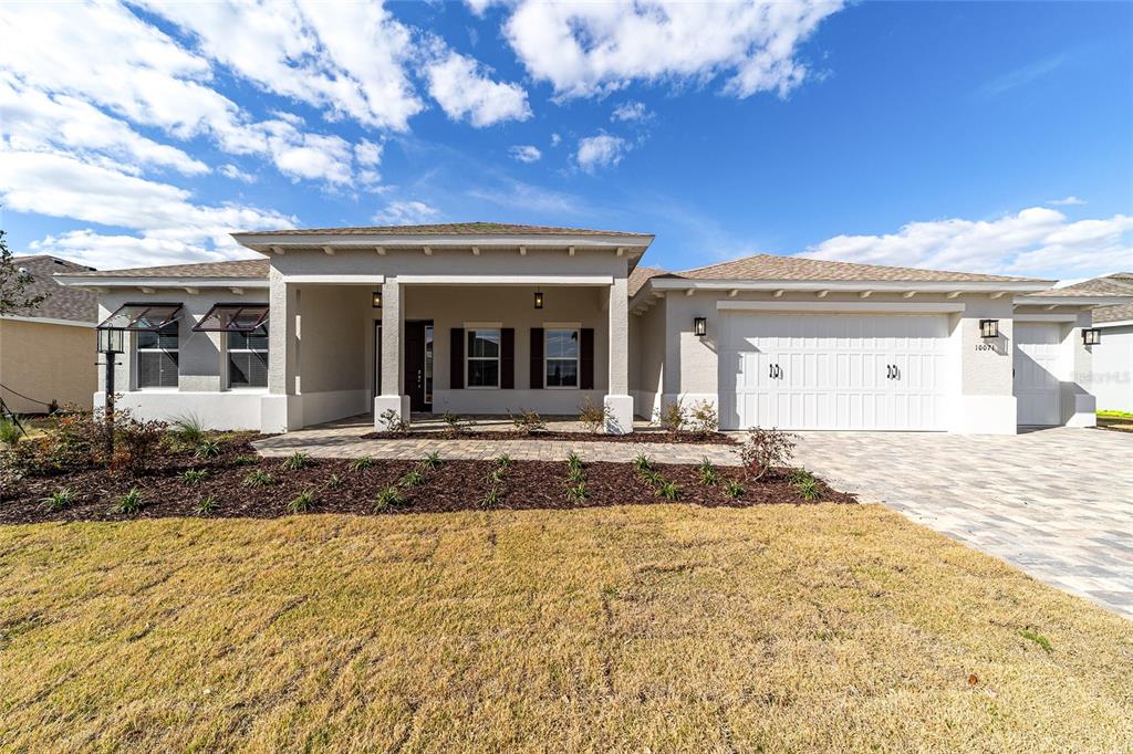 A single-story house with a beige stucco exterior, a paved driveway, and a covered entryway — 10071 SW 82ND PLACE ROAD, OCALA, FL