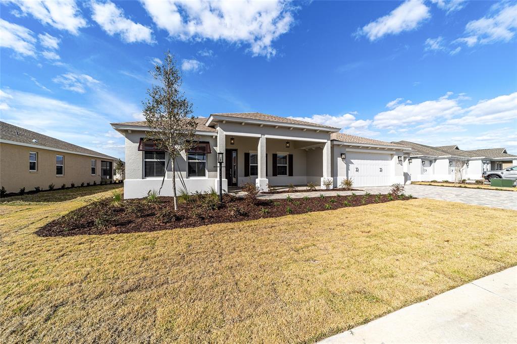 A single-story house with a beige stucco exterior, a covered entryway, and a two-car garage — 10071 SW 82ND PLACE ROAD, OCALA, FL