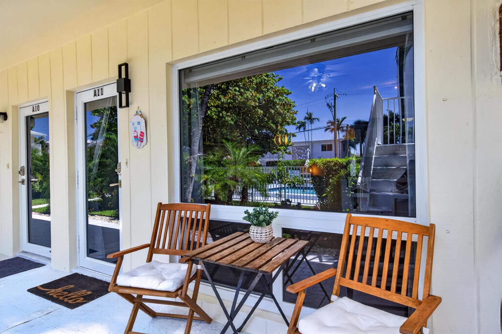 A patio area features two wooden chairs, a small table, and glass doors to units — 3201 SE 10th Street # A11, Pompano Beach FL 33062, POMPANO BEACH, FL
