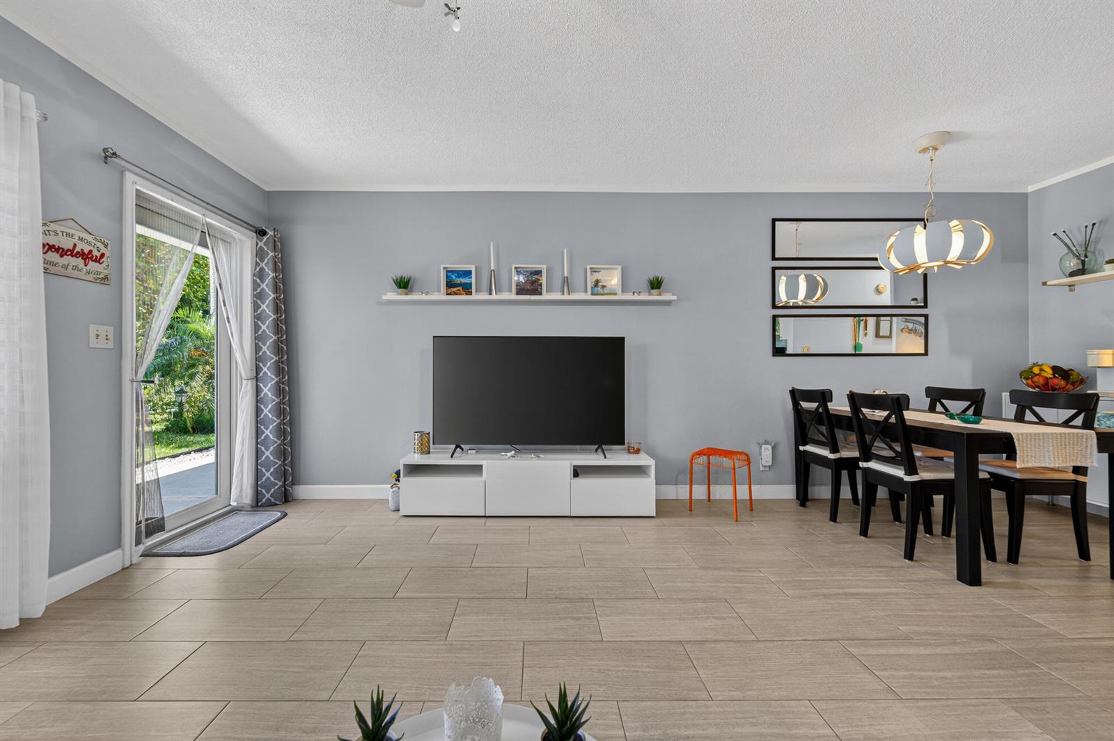 A living and dining area with light gray walls, tile flooring, and a sliding glass door — 3201 SE 10th Street # A11, Pompano Beach FL 33062, POMPANO BEACH, FL
