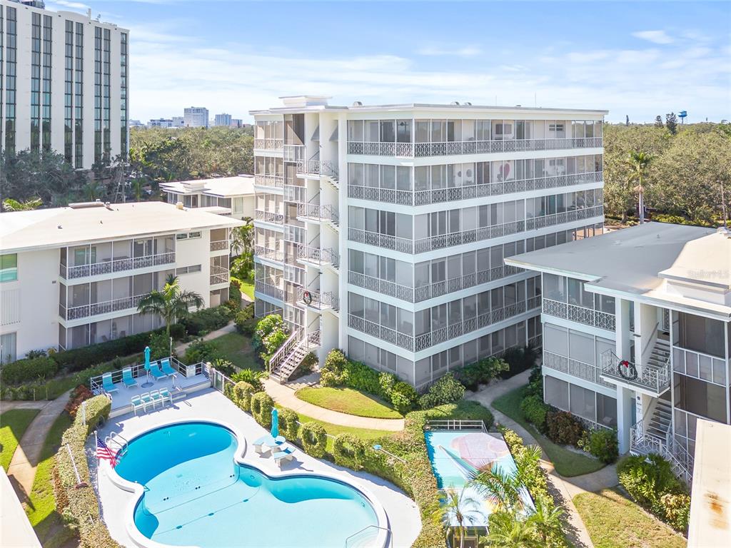 An aerial view shows a multi-story apartment building with screened balconies next to a swimming pool — 1012 N SHORE DRIVE NE UNIT 14, ST PETERSBURG, FL