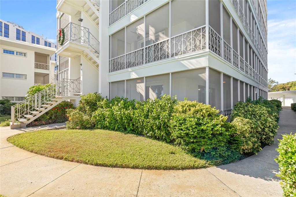An exterior view of a multi-story apartment building with screened-in balconies and a landscaped lawn — 1012 N SHORE DRIVE NE UNIT 14, ST PETERSBURG, FL