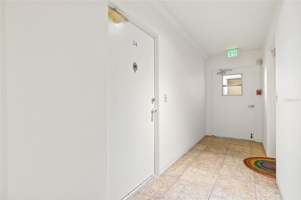 A white door labeled 14 sits in a hallway with tiled floors and an exit door — 1012 N SHORE DRIVE NE UNIT 14, ST PETERSBURG, FL