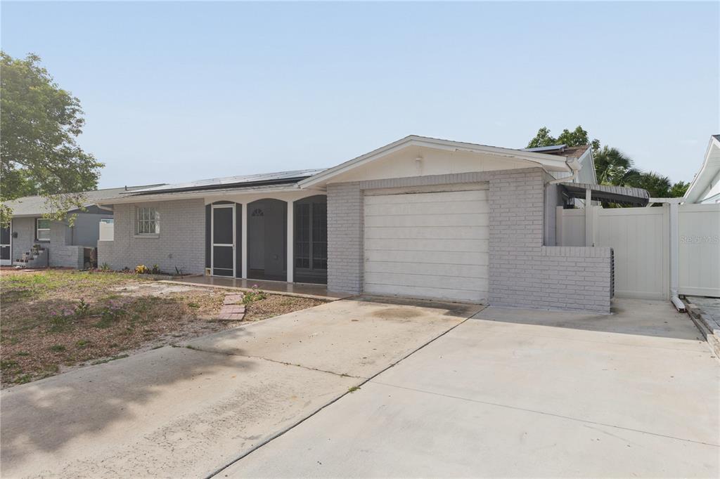 A single-story house with a light gray brick exterior, a one-car garage, and a concrete driveway — 6835 MESA VERDE STREET, PORT RICHEY, FL