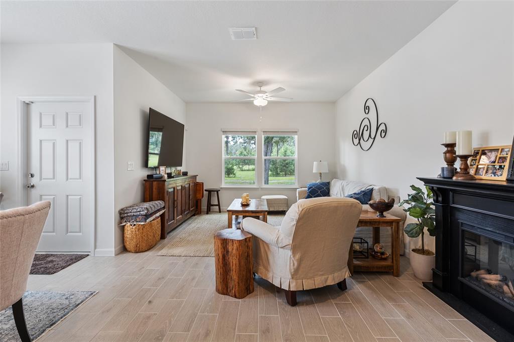 A living room features light tile flooring, a fireplace, a television, and a ceiling fan — 692 NW 126TH TERRACE UNIT 692, NEWBERRY, FL