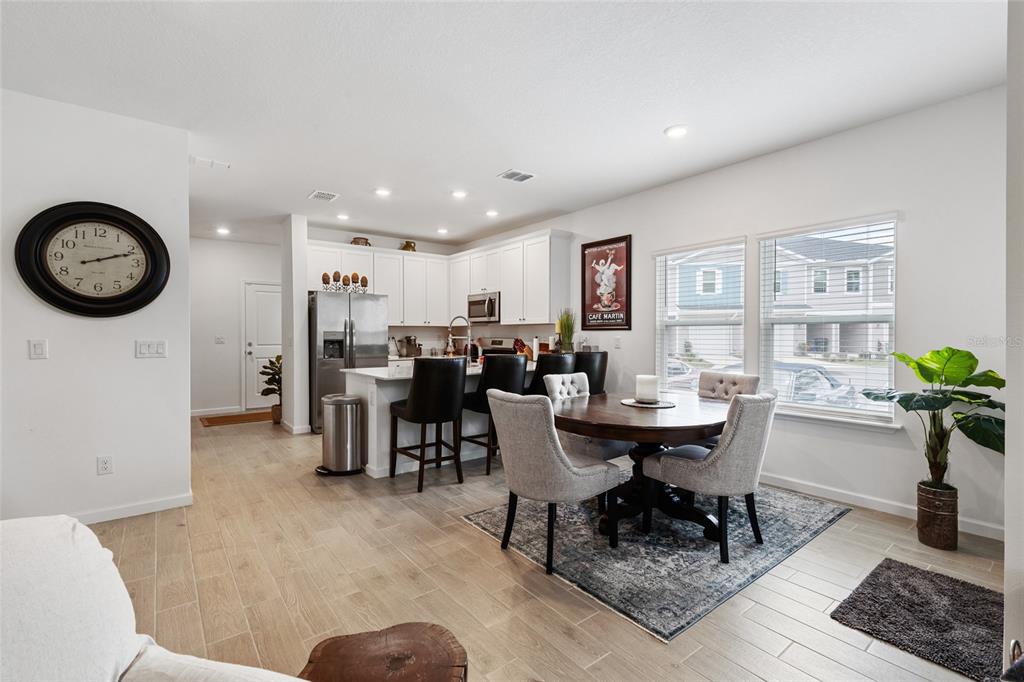 A kitchen with white cabinets and a dining area with a round table and chairs — 692 NW 126TH TERRACE UNIT 692, NEWBERRY, FL