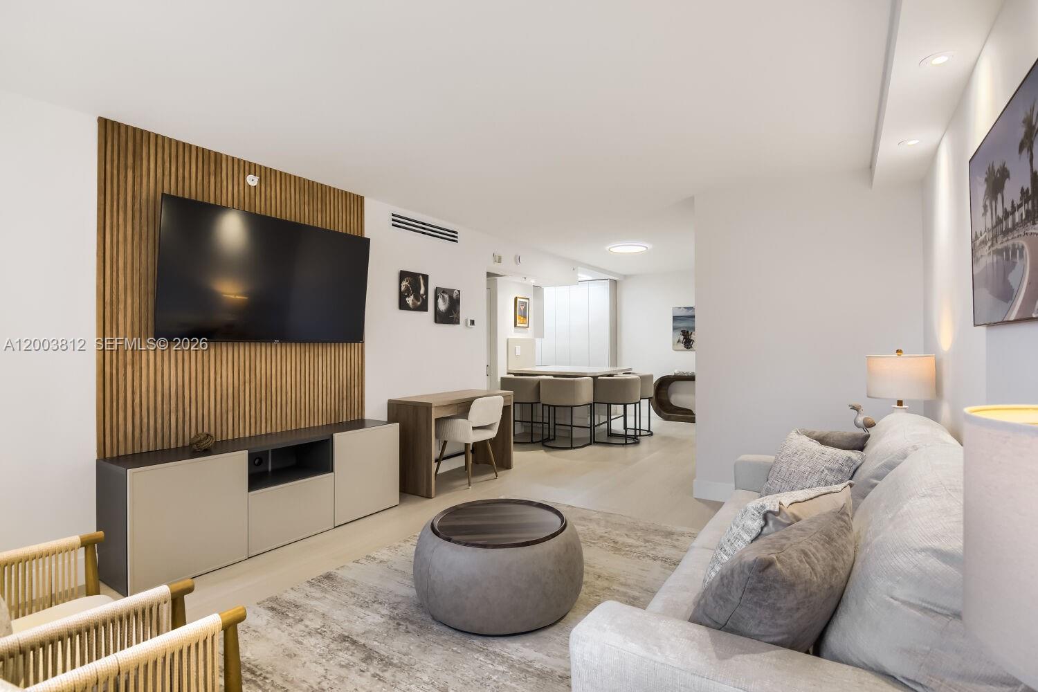 A modern living room features a slatted wood accent wall, television, and neutral furniture — 2501 S Ocean Dr # 833, Hollywood FL 33019, HOLLYWOOD, FL