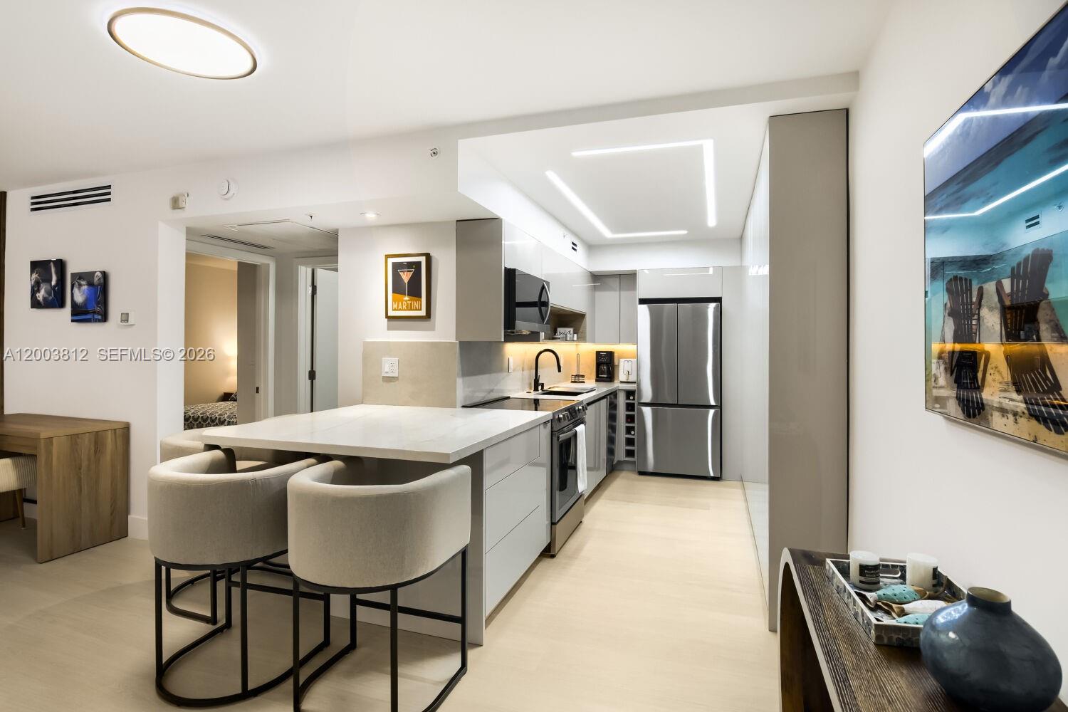 A modern kitchen features white cabinetry, a marble-topped island with bar stools, and stainless appliances — 2501 S Ocean Dr # 833, Hollywood FL 33019, HOLLYWOOD, FL
