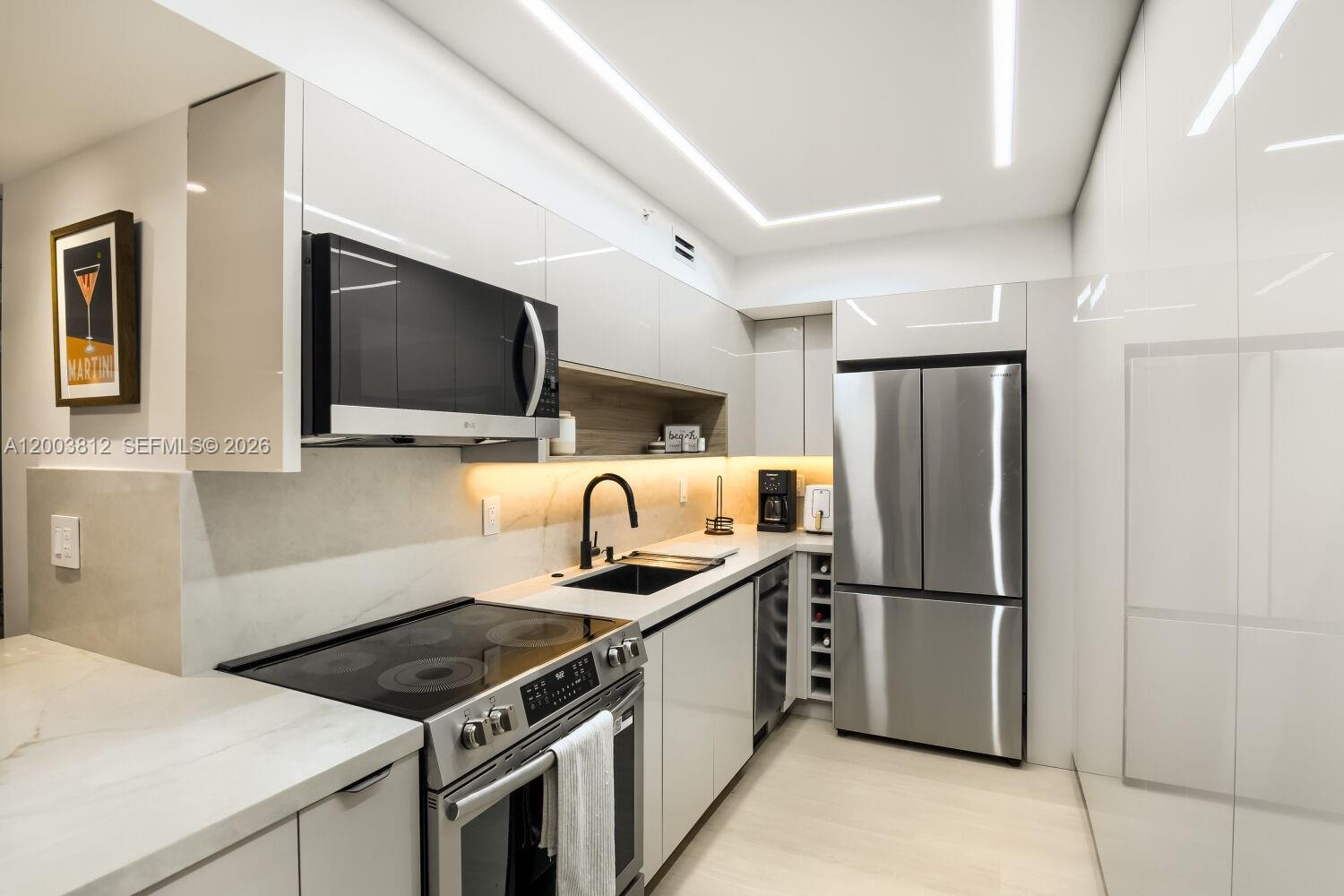 A modern kitchen features white glossy cabinets, stainless steel appliances, and a marble-style countertop — 2501 S Ocean Dr # 833, Hollywood FL 33019, HOLLYWOOD, FL