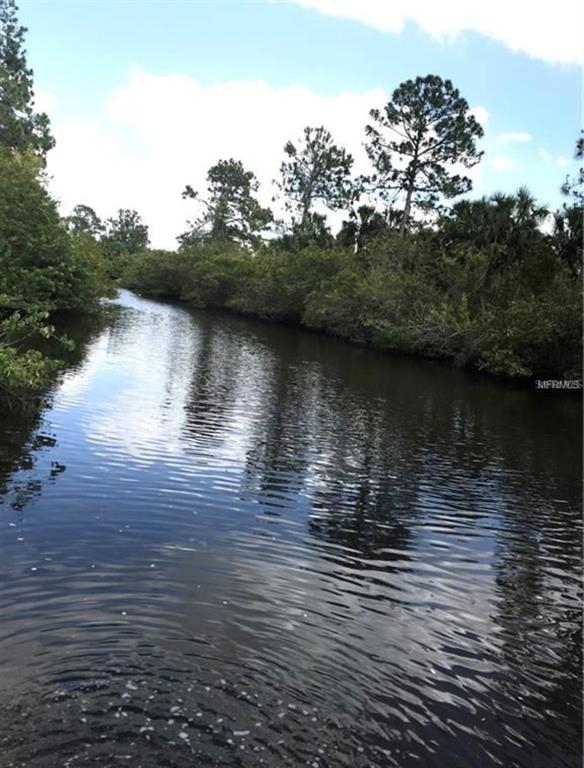 A narrow, dark waterway flows through a dense area of trees and lush vegetation — 14227 PITTENGER AVENUE, PORT CHARLOTTE, FL