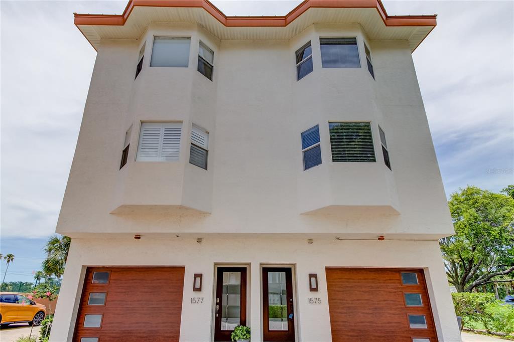 A two-story duplex building features two wooden garage doors and two front entry doors — 1575 PINELLAS BAYWAY WAY S UNIT 1575, TIERRA VERDE, FL