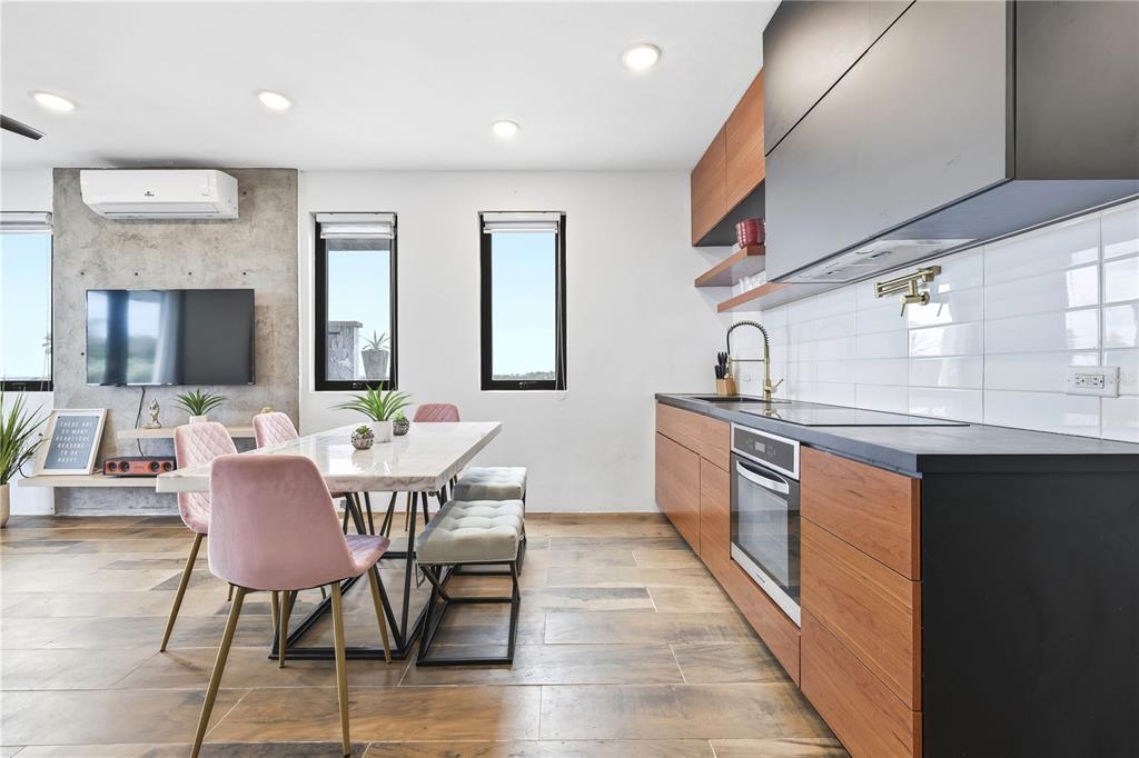 A modern kitchen and dining area features wood cabinets, a marble table, and pink chairs — Bo. Membrillo Solar 1, CAMUY, PR
