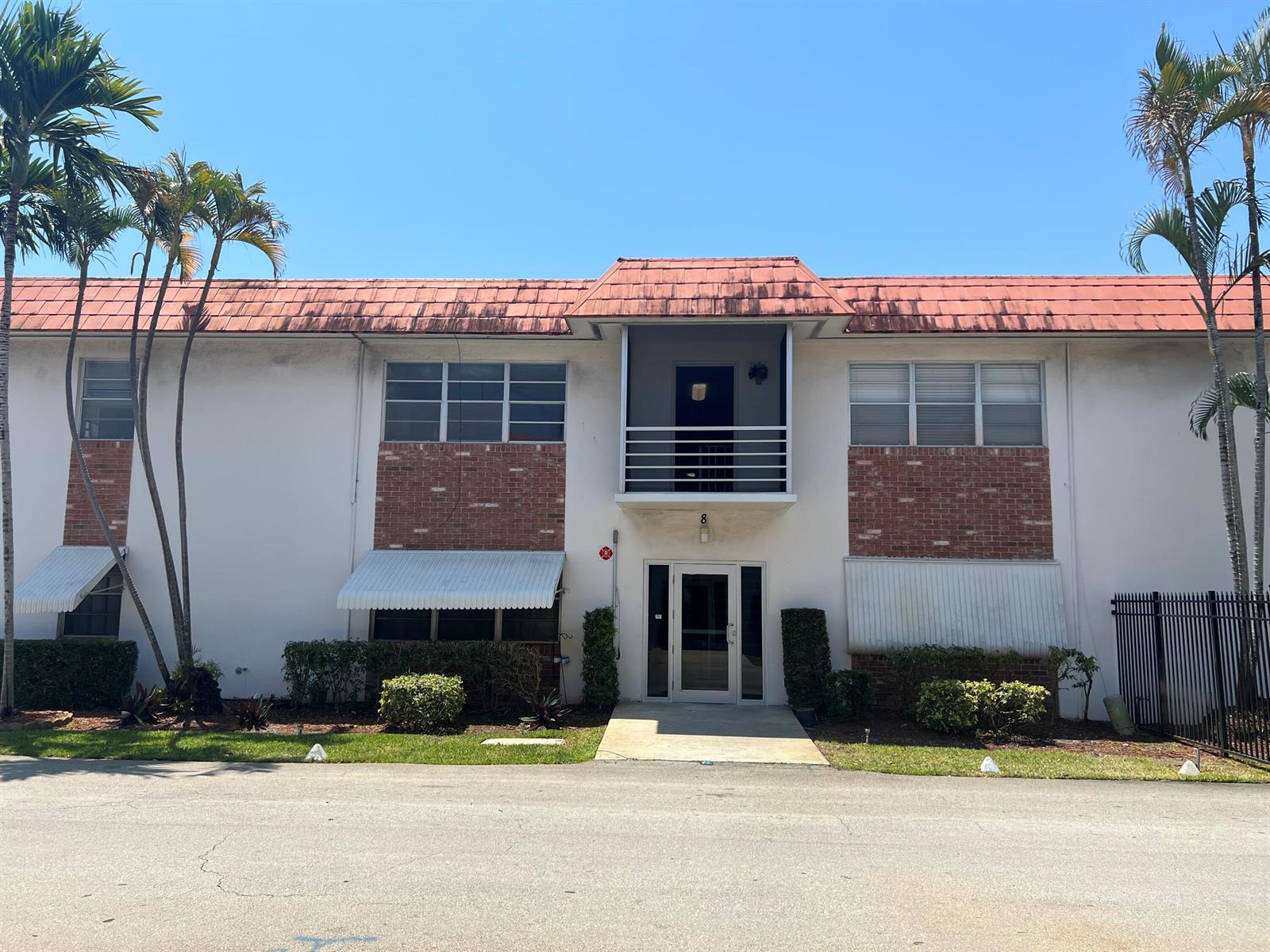 A two-story apartment building features a red tiled roof, brick accents, and a central balcony — 3550 NW 8th Avenue # 808, Pompano Beach FL 33064, POMPANO BEACH, FL