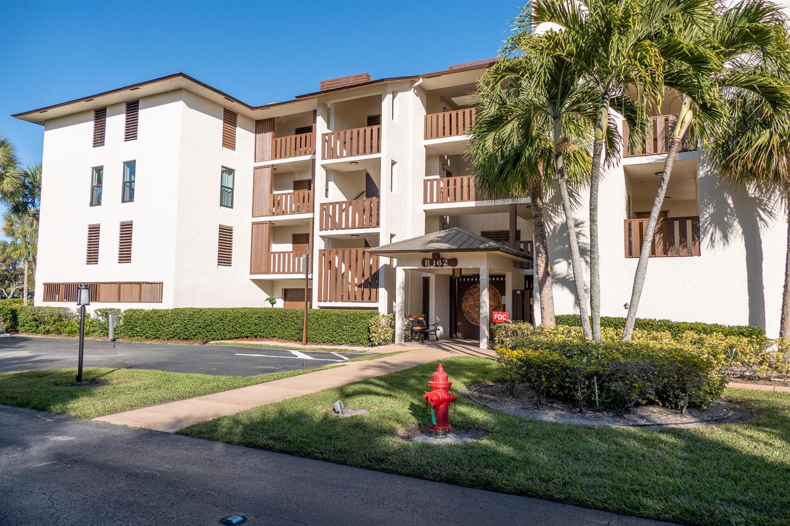 A multi-story apartment building exterior features a covered entrance, balconies, and a red fire hydrant — 162 SE Saint Lucie Boulevard # B403, Stuart FL 34996, STUART, FL