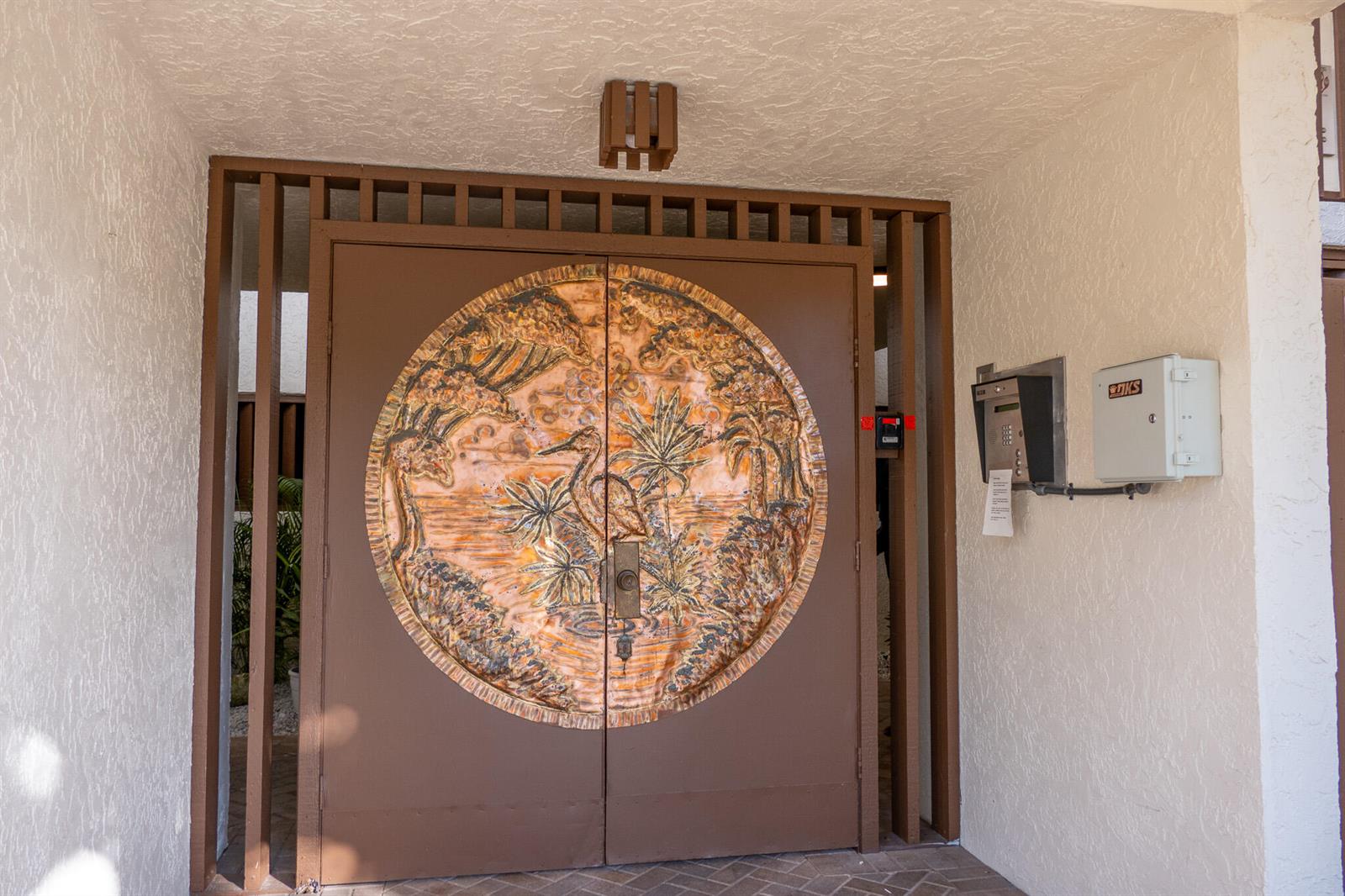 A brown double door features a large, circular, embossed metal panel depicting a tropical scene — 162 SE Saint Lucie Boulevard # B403, Stuart FL 34996, STUART, FL