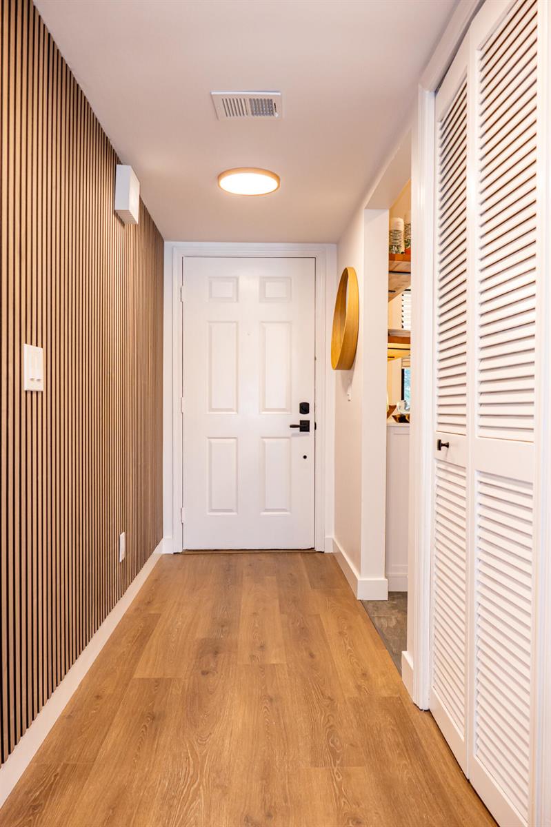 An entryway features wood-slat wall paneling, light wood flooring, a white door, and louvered closet doors — 162 SE Saint Lucie Boulevard # B403, Stuart FL 34996, STUART, FL