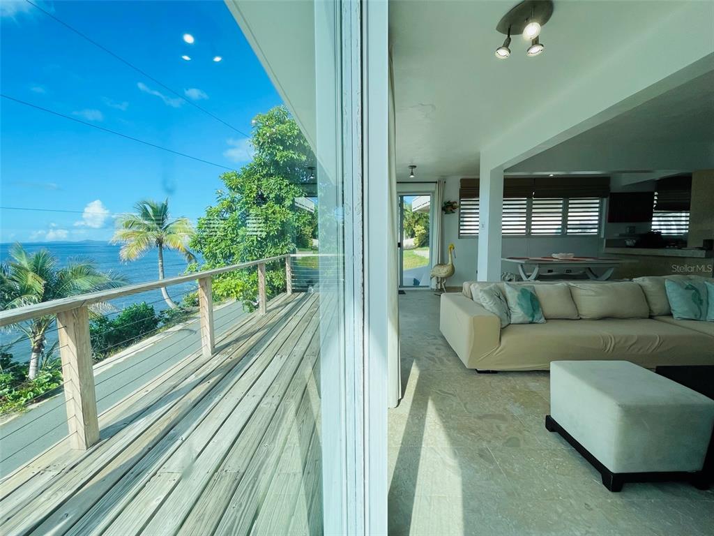 A living room with a large sectional sofa overlooks a wooden deck and the ocean — 56 N SHORE ROAD, VIEQUES, PR