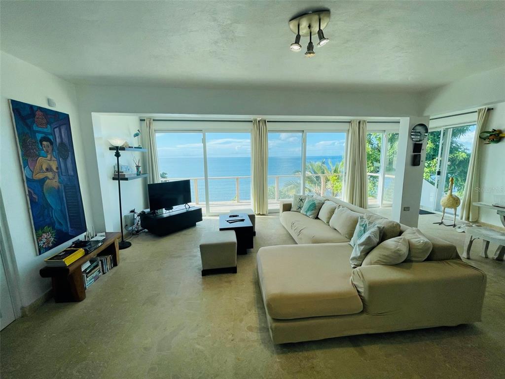 A living room features a large sectional sofa, tile floors, and sliding doors overlooking the ocean — 56 N SHORE ROAD, VIEQUES, PR