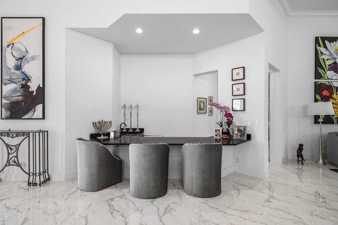 A modern home bar features a black countertop, three gray chairs, and marble flooring — 6517 Somerset Circle, Boca Raton FL 33496, BOCA RATON, FL