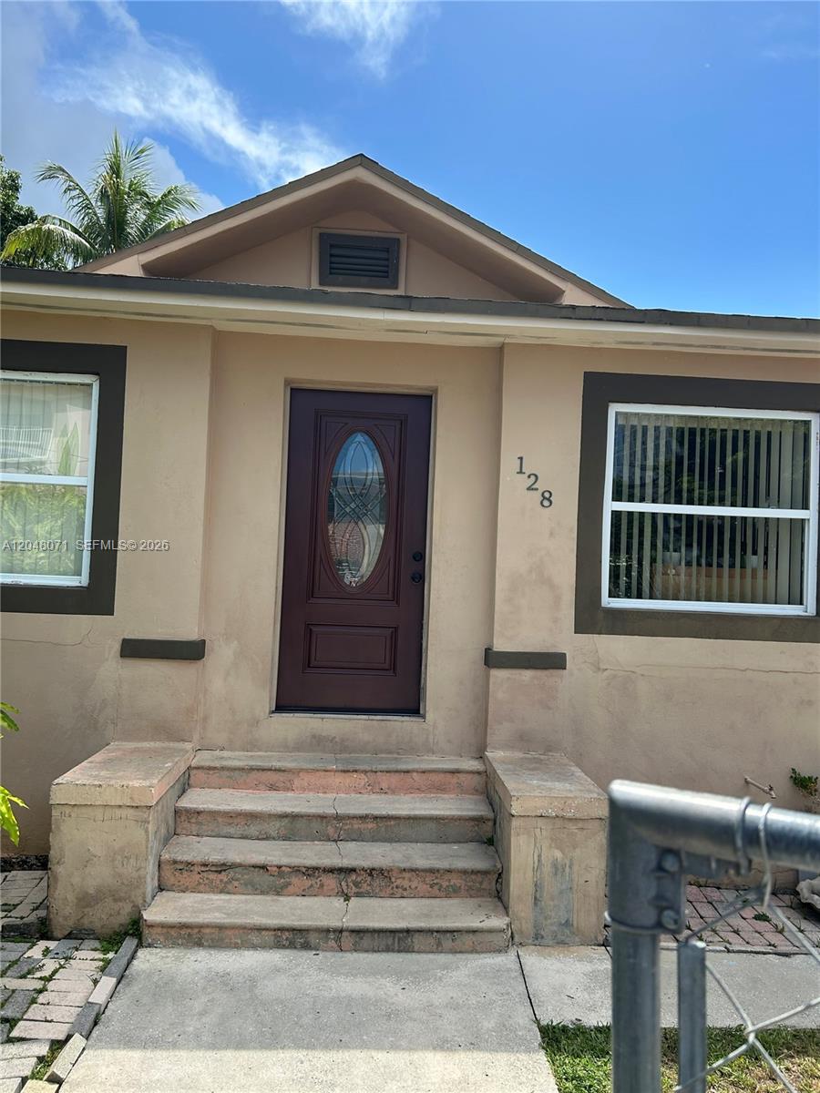 The exterior of a tan house features a dark brown front door and concrete steps — 128 SW 11th Ave, Miami FL 33130, MIAMI, FL