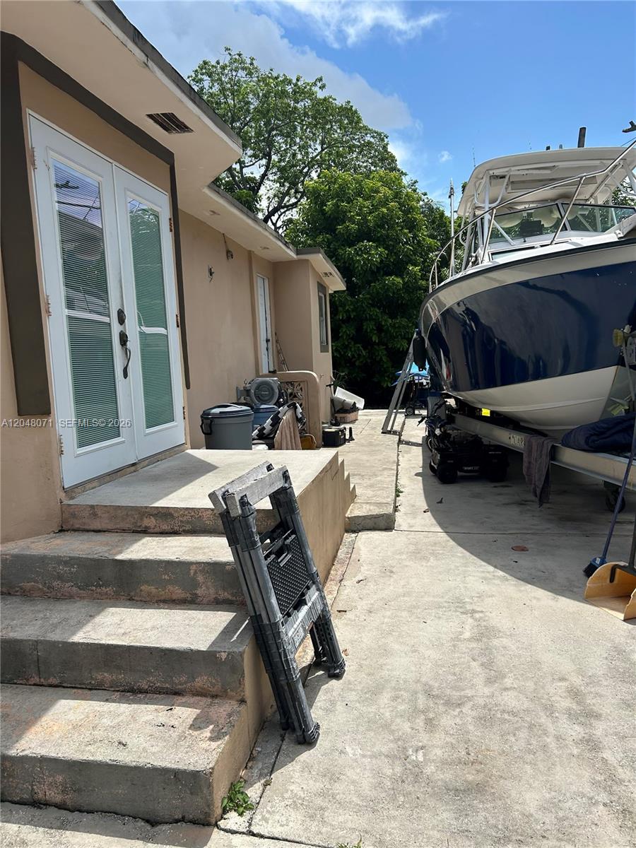 An exterior view shows a concrete walkway, steps leading to double doors, and a boat — 128 SW 11th Ave, Miami FL 33130, MIAMI, FL