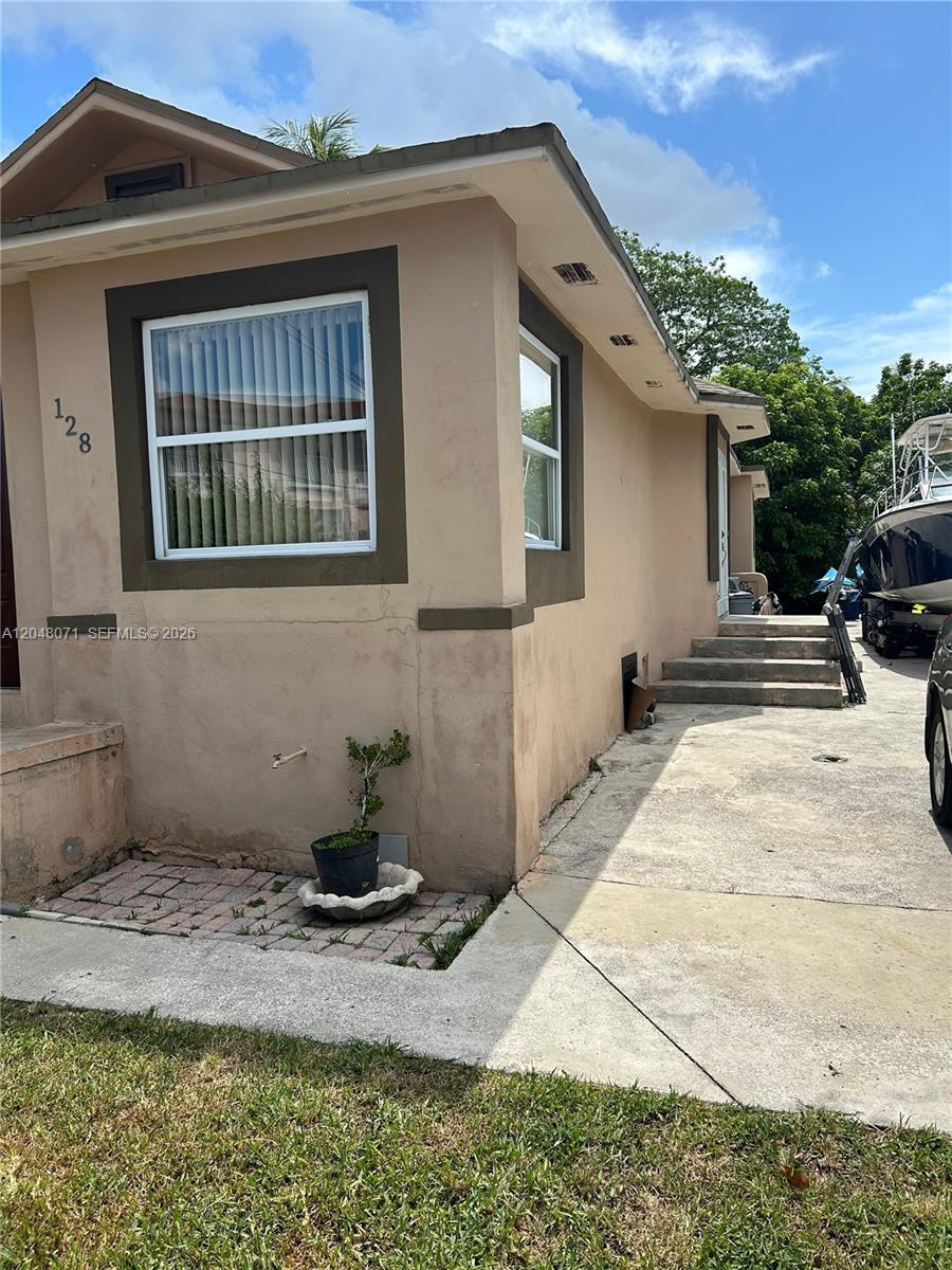 The exterior of a beige house features a window, a small potted plant, and stairs — 128 SW 11th Ave, Miami FL 33130, MIAMI, FL