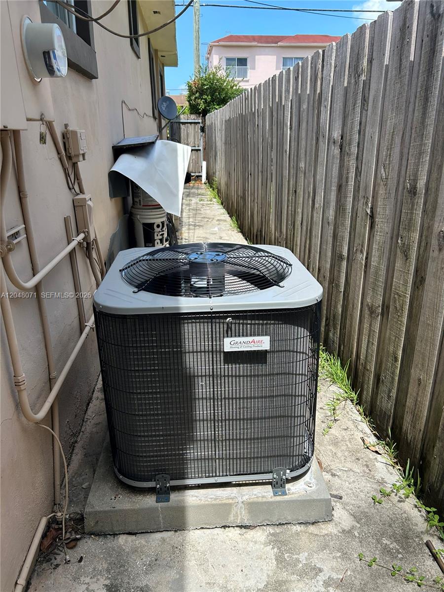 An outdoor air conditioning unit sits on a concrete pad beside a wooden fence — 128 SW 11th Ave, Miami FL 33130, MIAMI, FL
