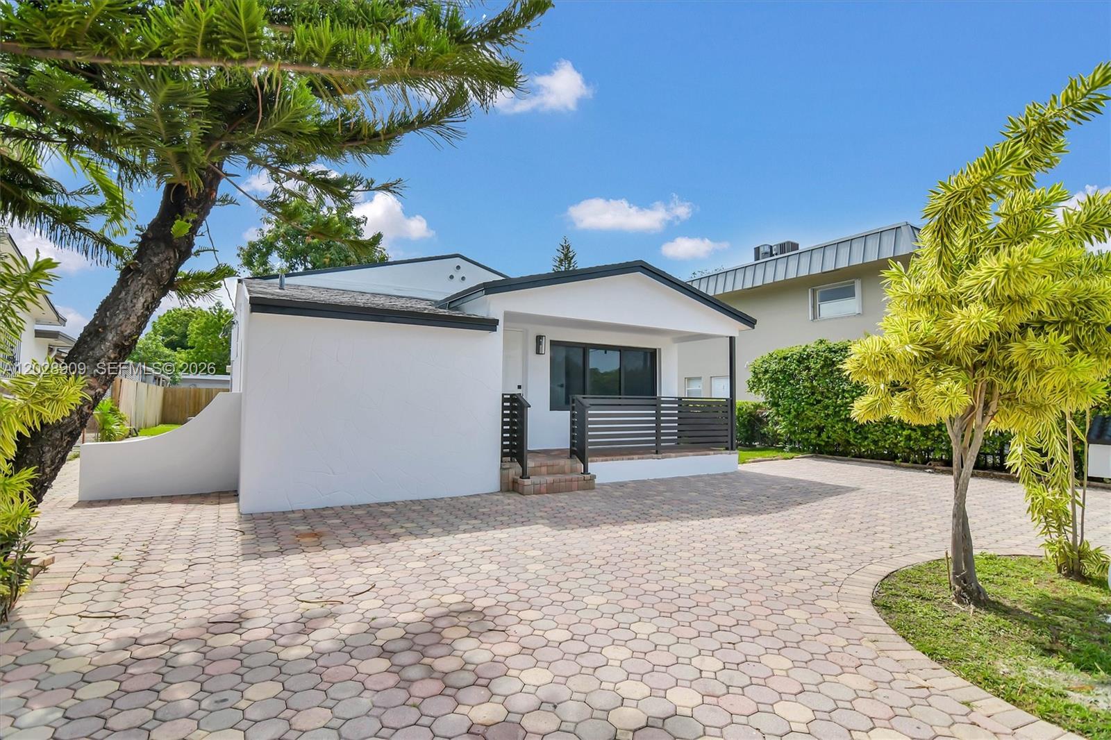 A white house with a dark-trimmed porch sits behind a large paved driveway — 85 SW 30th Ave, Miami FL 33135, MIAMI, FL