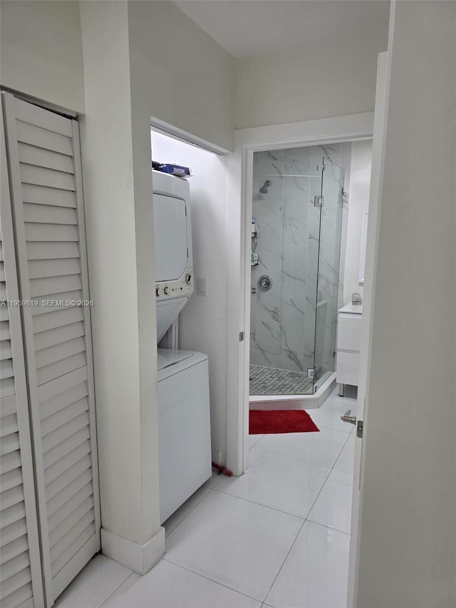 A laundry closet with a stacked washer and dryer sits beside a tiled bathroom entrance — 8523 NW 35th Pl, Miami FL 33147, MIAMI, FL