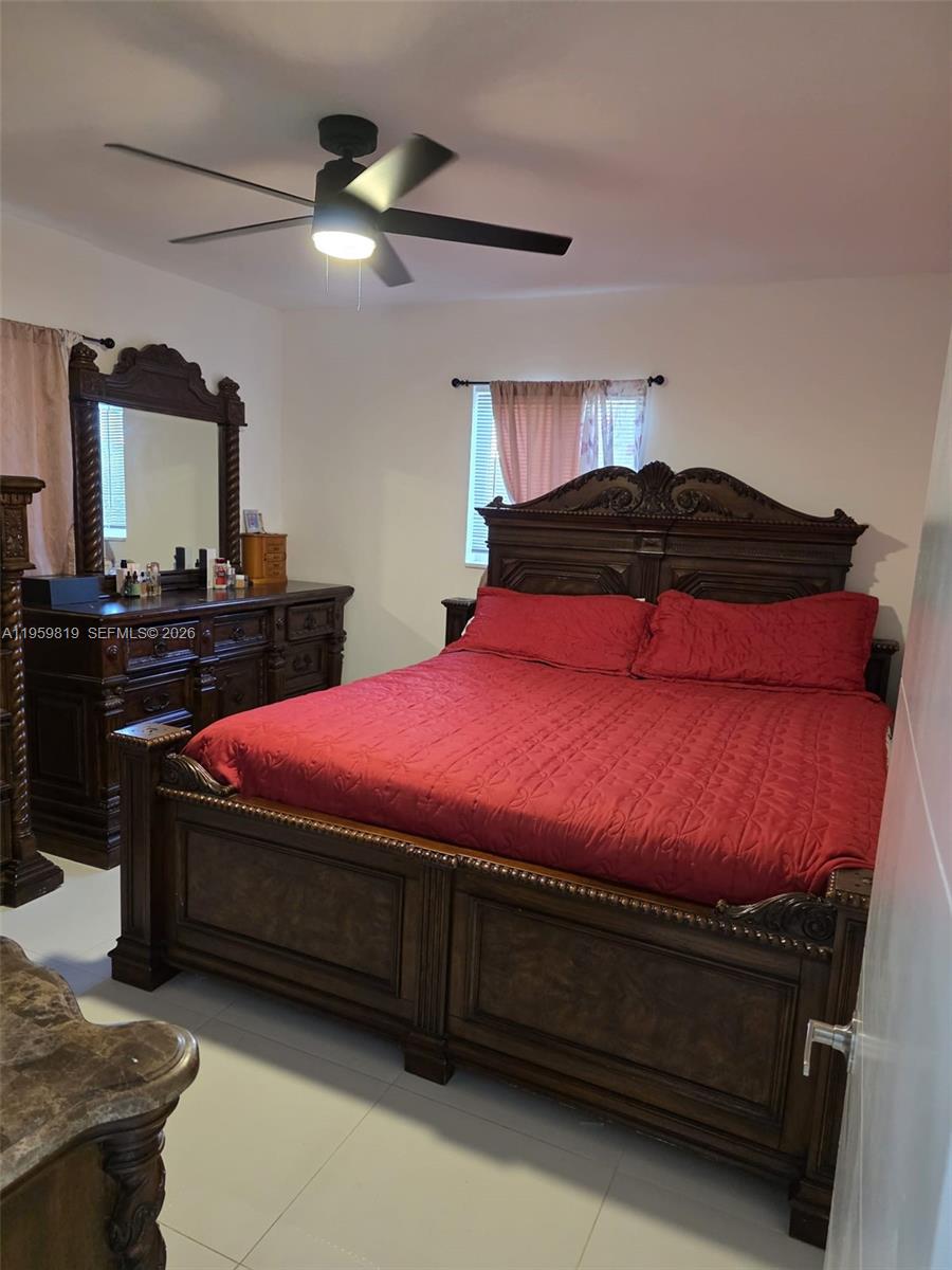A bedroom features a large dark wood bed frame, matching dresser with mirror, and red bedding — 8523 NW 35th Pl, Miami FL 33147, MIAMI, FL