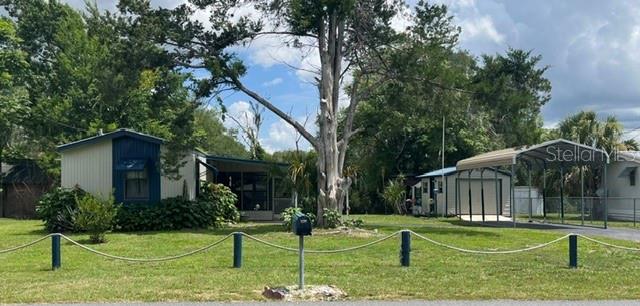 A mobile home with a carport and a large tree in the front yard — 10019 E BLUEGILL COURT, INVERNESS, FL