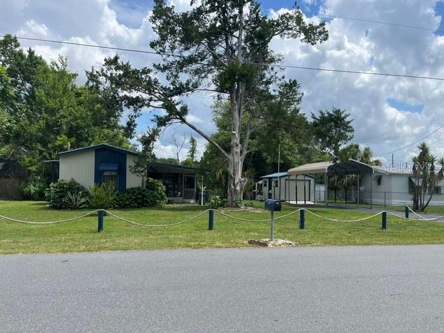 A single-story house with a carport and a large tree in the front yard — 10019 E BLUEGILL COURT, INVERNESS, FL
