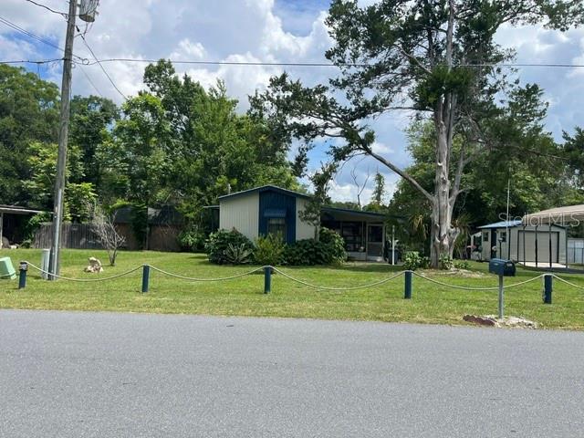 A single-story house with a blue-trimmed porch sits on a grassy lot with mature trees — 10019 E BLUEGILL COURT, INVERNESS, FL