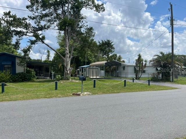 A view of a mobile home with a carport and a large tree in front — 10019 E BLUEGILL COURT, INVERNESS, FL