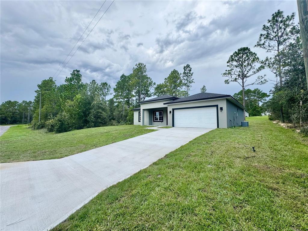 A modern, single-story house with a concrete driveway and a two-car garage — 7035 N MALTESE DRIVE, CITRUS SPRINGS, FL