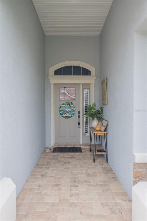 A covered entryway features a light gray front door with a transom window and pavers — 7914 LAKE JAMES BOULEVARD, LAKELAND, FL