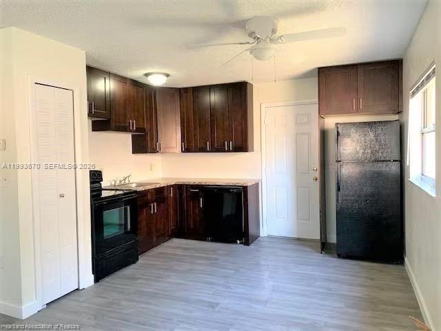 A kitchen features dark wood cabinets, black appliances, and light gray wood-look flooring — 425 Las Palmas # 612, Avon Park FL 33825, AVON PARK, FL