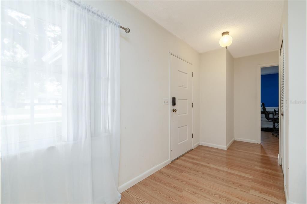 An entryway features light wood-look flooring, a white front door, and a window with curtains — 1987 S OLD MILL DRIVE, DELTONA, FL