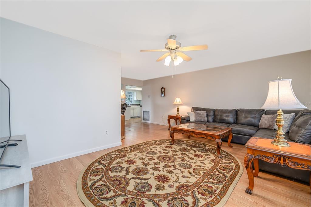 A living room features a dark leather sectional, an oval patterned rug, and wood flooring — 1987 S OLD MILL DRIVE, DELTONA, FL