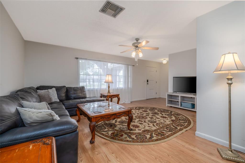 A living room features a dark leather sectional, a coffee table, and a round rug — 1987 S OLD MILL DRIVE, DELTONA, FL