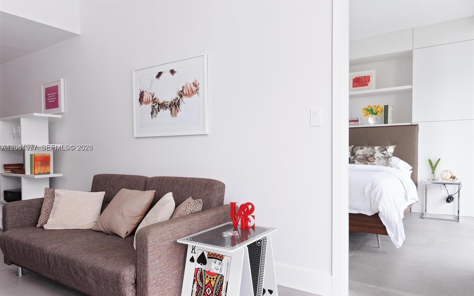 A living area with a brown sofa and a playing card side table leads into a bedroom — 1300 S Miami Ave # 3311, Miami FL 33130, MIAMI, FL