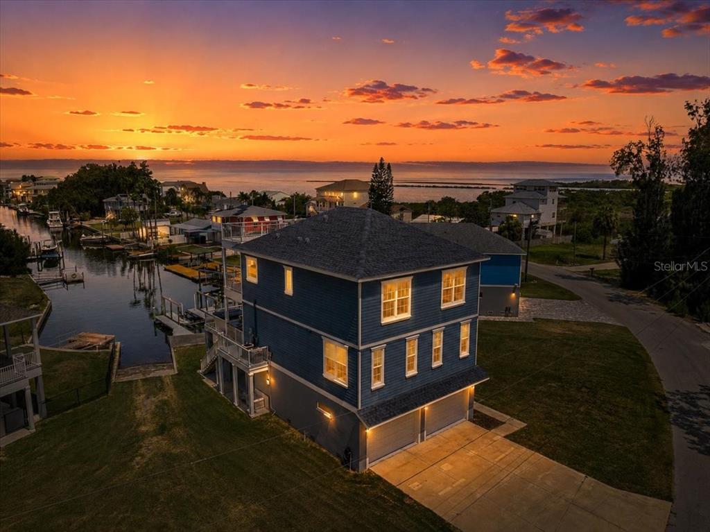 An aerial view of a blue multi-story house with a garage at sunset — 6812 DRIFTWOOD DRIVE, HUDSON, FL