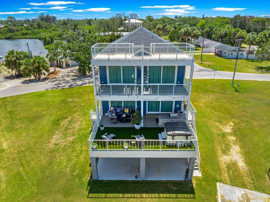 An elevated three-story house features multiple balconies, a rooftop deck, and a ground-level patio area — 6812 DRIFTWOOD DRIVE, HUDSON, FL