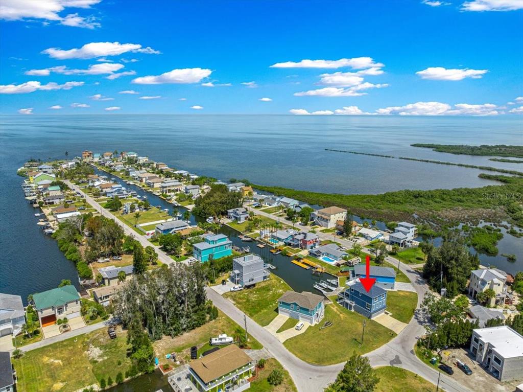 An aerial view shows a blue house with a red arrow pointing to its roof — 6812 DRIFTWOOD DRIVE, HUDSON, FL